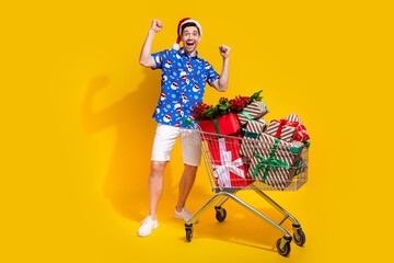 Poster - Full length portrait of delighted person raise fists purchase pile stack giftbox hypermarket trolley isolated on yellow color background