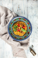 Canvas Print - Pilaf with lamb in a plate with national Uzbek ornaments. vertical image. top view. place for text