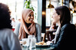 © Jasmina - Happy smiling female friends sitting in a café laughing and talking during a lunch break