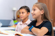© Chiralli - Teacher and school student children studying at desk in educational classroom, writing in notebook, reading book. Group of diverse classmates learning. Academic Concept.