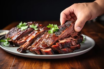 Sticker - hand adjusting garnish on plate of applewood smoked pork ribs