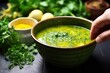 hand garnishing detox soup with a sprinkle of herbs