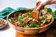 hand moving the salad tongs through a bowl of farro salad