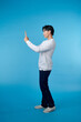 © makistock - Handsome young man taking selfie on blue background
