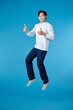© makistock - Young Asian man jumping and showing thumbs up isolated on blue background