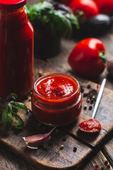 Wall Mural - Ketchup in a jar. Tomato sauce on a dark background