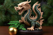 Green wooden dragon figurine on a table with fir branches in the background. Symbol of the New Year.