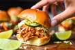 squeezing a lime wedge over spicy bbq pork slider
