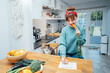 © okrasiuk - Young woman filling veganuary calendar while eating fresh carrot sitting on kitchen. Fresh vegetables and fruits on table. Vegan and vegetarian diet eating and cooking at home. Selective focus