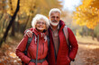 © Olga - Senior active mature couple walks in the park with hiking backpacks