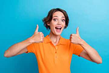 Canvas Print - Photo of good mood excited lady wear orange t-shirt open mouth showing two thumbs up isolated blue color background