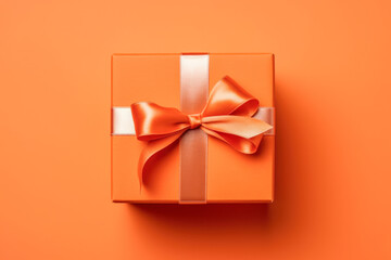 Orange gift box with ribbon and bow isolated on orange background.Holiday gift with Birthday, Christmas present or Halloween, flat lay, top view, copy space