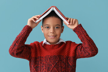 Poster - Cute African-American boy in knitted sweater and with book on blue background