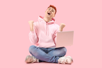 Canvas Print - Happy young redhead man with laptop on pink background