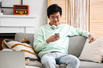 Poster - Young Asian man using mobile phone on his day off at home