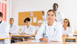 © JackF - Young woman medical student in white coat attedning classes in university, sitting at desk and listening to lecture.