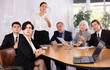 © JackF - Young adult old office workers sitting at table and looking at screen while young female using projector remote control in meeting room