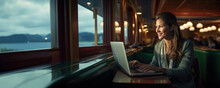 Caucasian woman working remotely on her laptop in a cruise ship, concept of living as a digital nomad and entrepreneurship