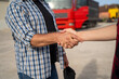 Unrecognizable Truck driver shaking hands with fleet manager , truck blurred in background. closeup shot