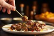 hand sliding cooked meatballs off skewer onto a dish