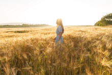 Girl Standing Amidst Wheat Crop On Sunny Day In Field