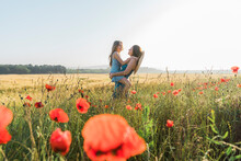 Happy Mother Carrying Daughter In Poppy Field