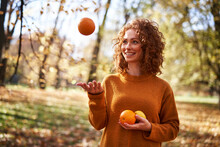 Smiling Redhead Woman Playing With Oranges And Lemon At Autumn Park