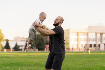 Wall Mural - happy father and son outdoors, little kid raised in the air