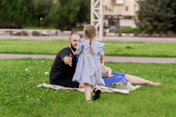 Wall Mural - mom and dad laying on the lawn and hug daughter running to them