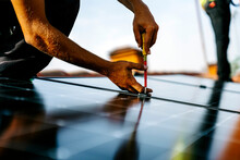 Hands of engineer using screwdriver to install solar panels