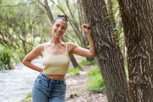Smiling Woman Leaning On Tree In Forest