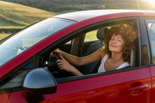 Smiling Woman With Eyes Closed Driving Red Car