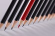 Red pencil separating row of black pencils. Business concept for leadership or thinking differently