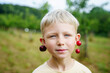 © Westend61 - Blond boy wearing cherries on ears in garden