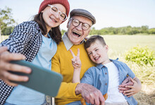 Happy Girl Taking Selfie With Brother And Grandfather Through Mobile Phone