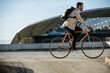 © Westend61 - Man with backpack riding bicycle in parking lot on sunny day