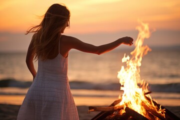 woman in a sundress dancing by a beach bonfire