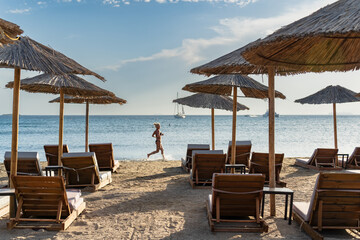 Wall Mural - A girl in a bikini runs on the beach in Greece in the morning.