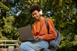© Nomad_Soul - Happy smiling male student wearing wireless headphones using laptop