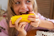 © Nataliia Makarovska - happy girl opens her mouth to eat hot yellow sweet corn with salt and butter holding it with both hands