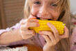 © Nataliia Makarovska - happy girl opens her mouth to eat hot yellow sweet corn with salt and butter holding it with both hands