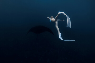 Wall Mural - Woman underwater with manta ray. Freediving with manta rays on deep ocean