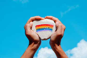 Sticker - holds a rock with the rainbow flag painted in it