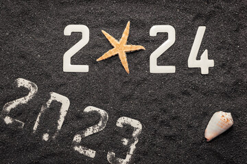 Wall Mural - Bonne année 2024 : Concept de nouvelle année 2024 sur le sable noir d'une plage et les chiffres 2024 vu du dessus.