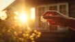 © ND STOCK - An image of a woman holding a key and a wooden house silhouette against the sun. Home ownership concept, real estate concept