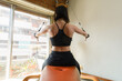 rear view of caucasian woman in black sportswear training back and shoulder on pulley machine at home.