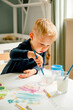 © Franci Leoncio - A male caucasian toddler is painting with watercolor