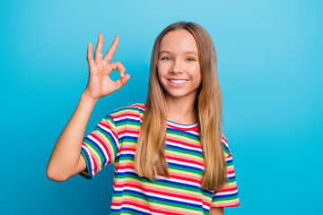 Poster - Portrait of optimistic schoolgirl with long hairstyle wear colorful t-shirt showing okey good job isolated on blue color background