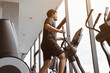Fitness male is training on exercise elliptical machine. Healthy man is working out in gym.