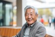 Portrait of smiling senior Asian man sitting on a bench outside